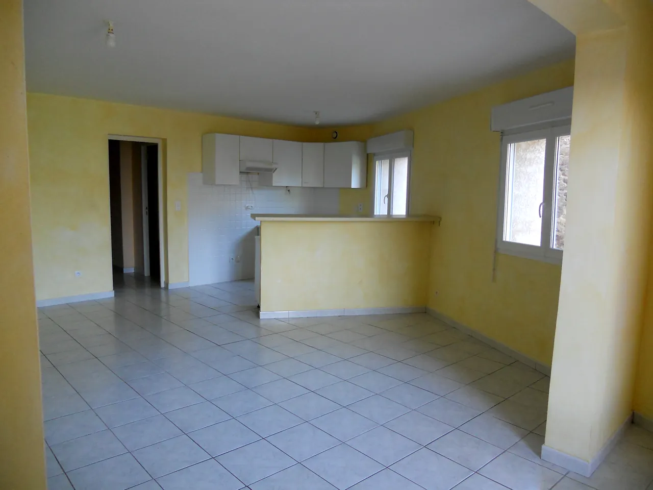 Séjour lumineux du duplex de 116 m², avec la cuisine et son bar au fond